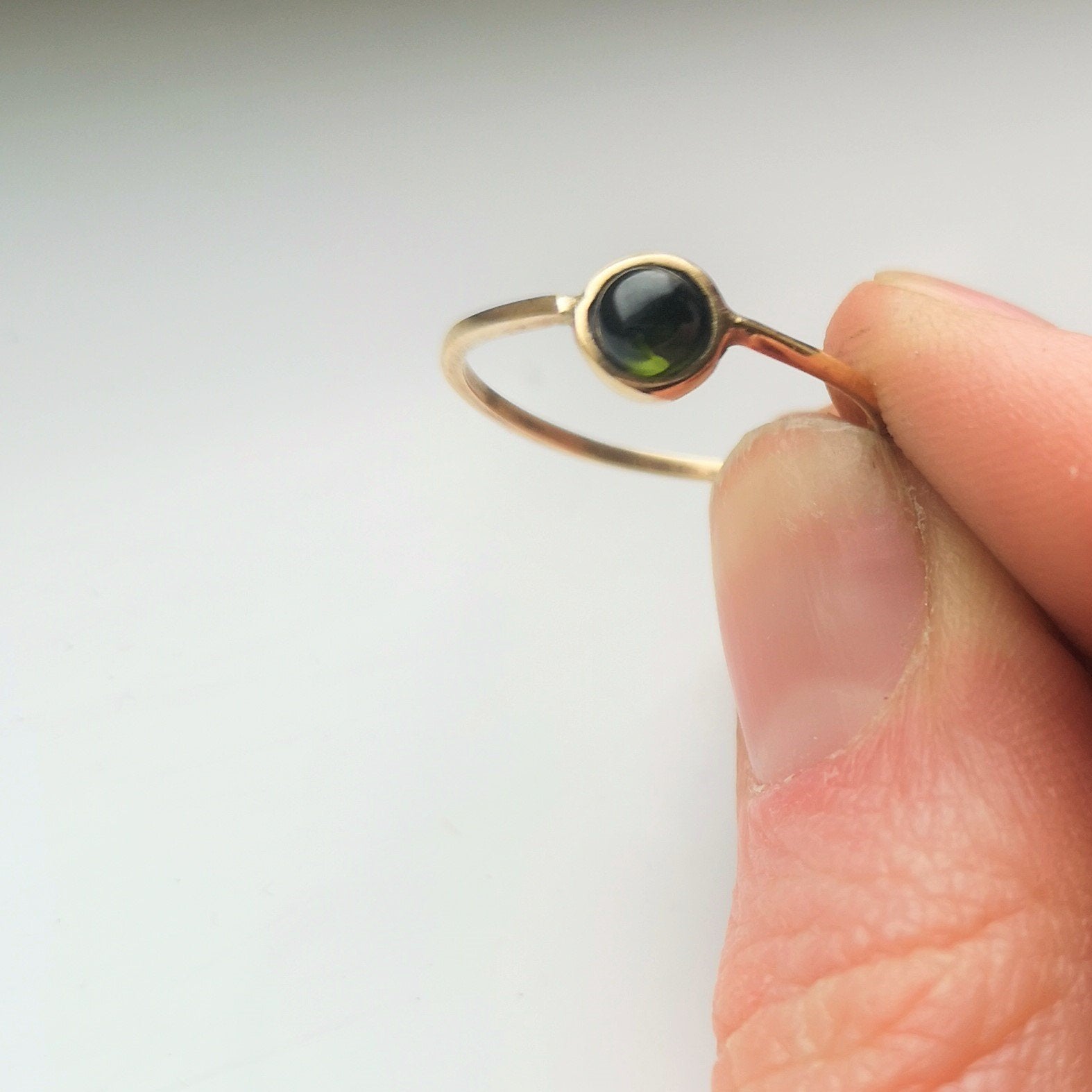 Simple minimal solid gold green tourmaline ring.